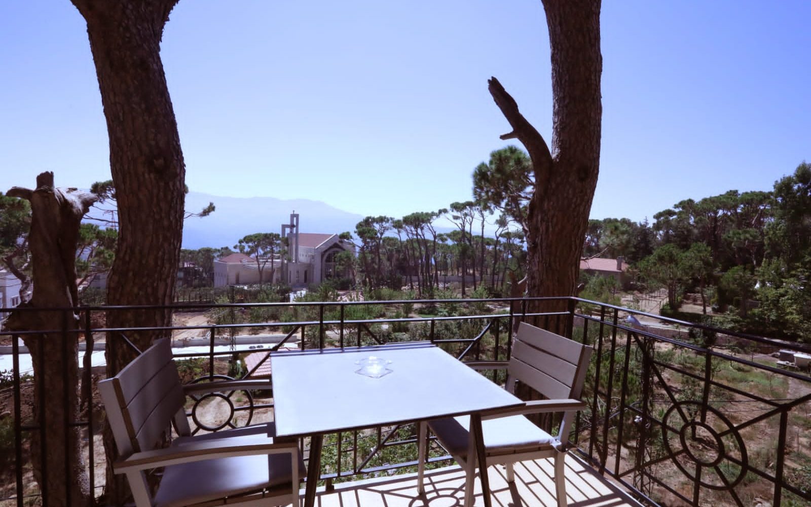 A balcony table looking out through the pines over the Metn at dusk