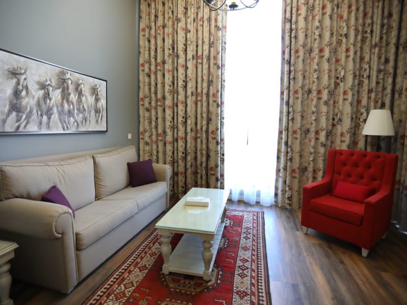 A suite sitting room with floral curtains and a red armchair